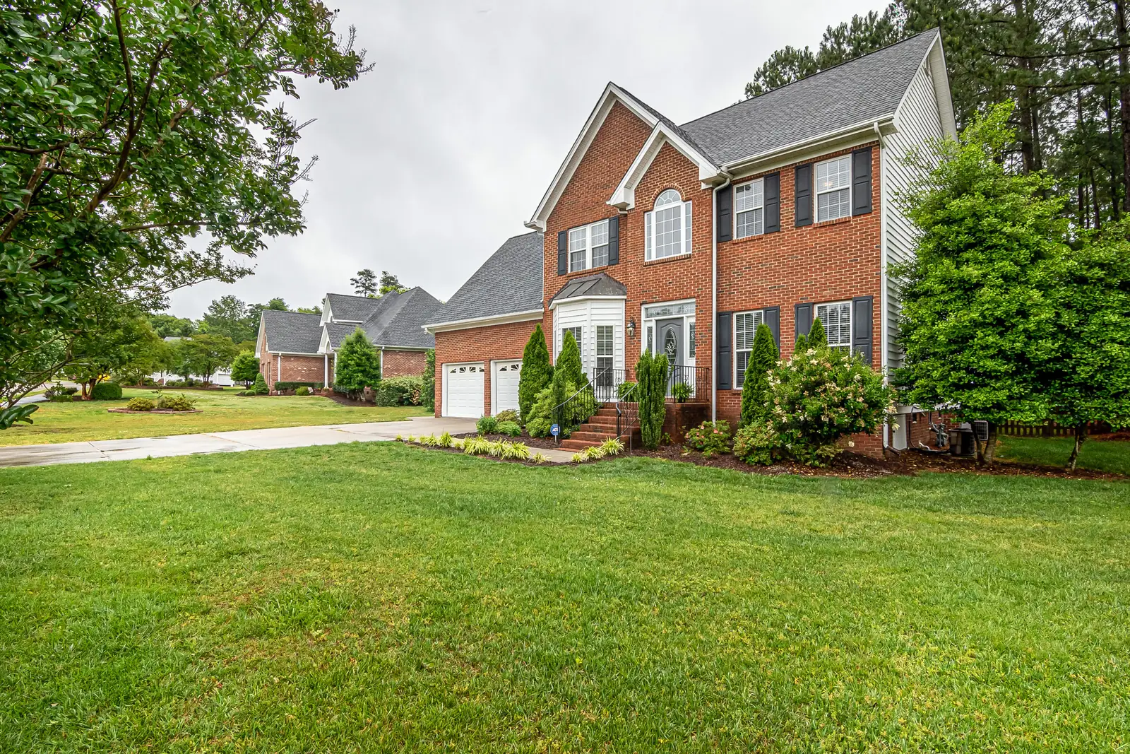 A two-storey brick home with a freshly cut lawn and mature trees